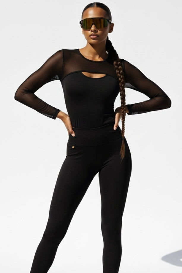 Le mesh à l'empiècement et aux manches est transparent, le milieu opaque. Le legging a un petit logo doré.