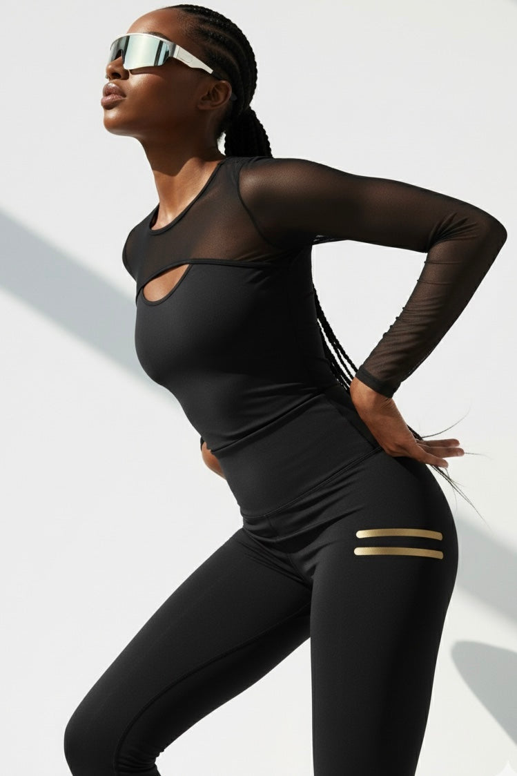 Penché en arrière dans le haut. Le legging noir a deux courtes rayures dorées sur la cuisse.