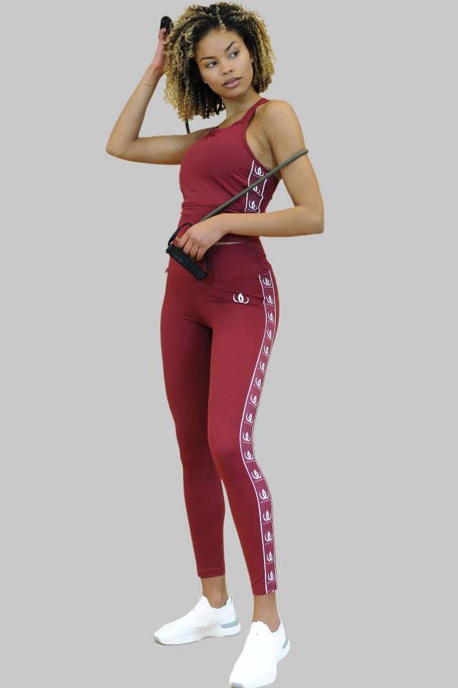Une corde à sauter à la main, le legging bordeaux se porte avec un crop top de la même couleur.