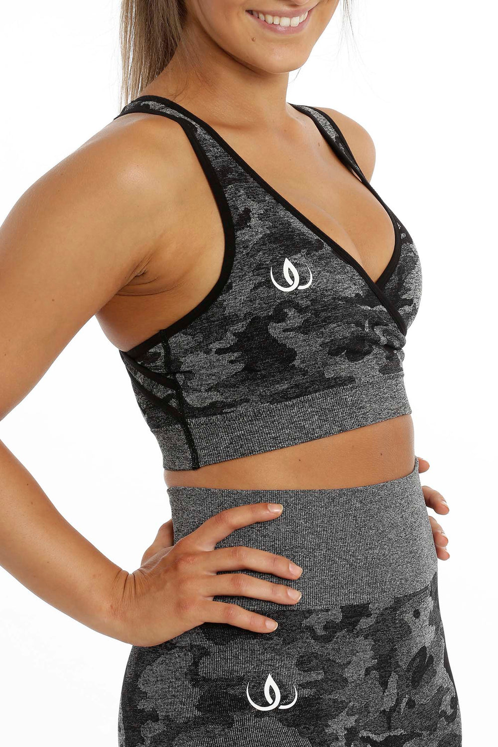 Le haut vu de trois quarts avec un logo blanc sur la poitrine, au-dessus d'un legging dans le même camouflage.