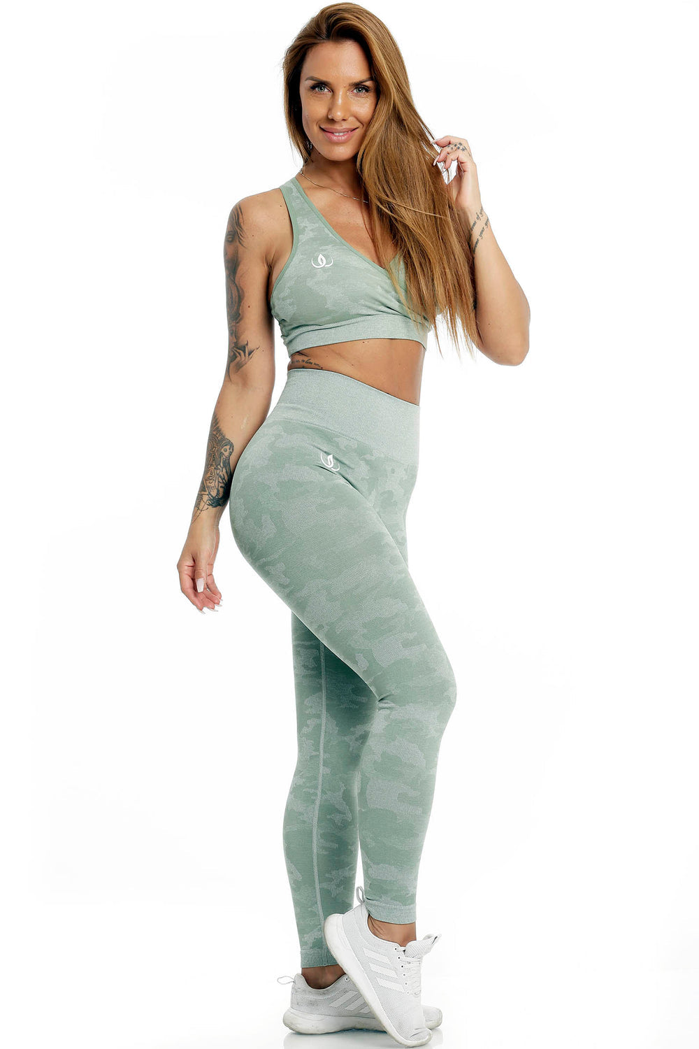 Le mannequin se tient debout dans le haut vert menthe et un legging à imprimé camouflage, avec des chaussures blanches.