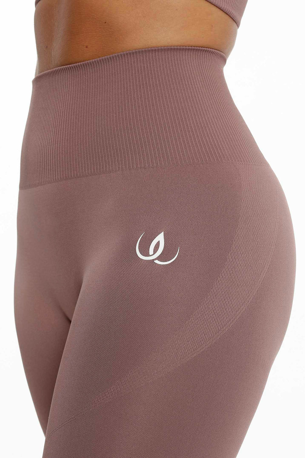 La ceinture côtelée et le logo blanc à la hanche, le tissu dans un ton brun rosé feutré.