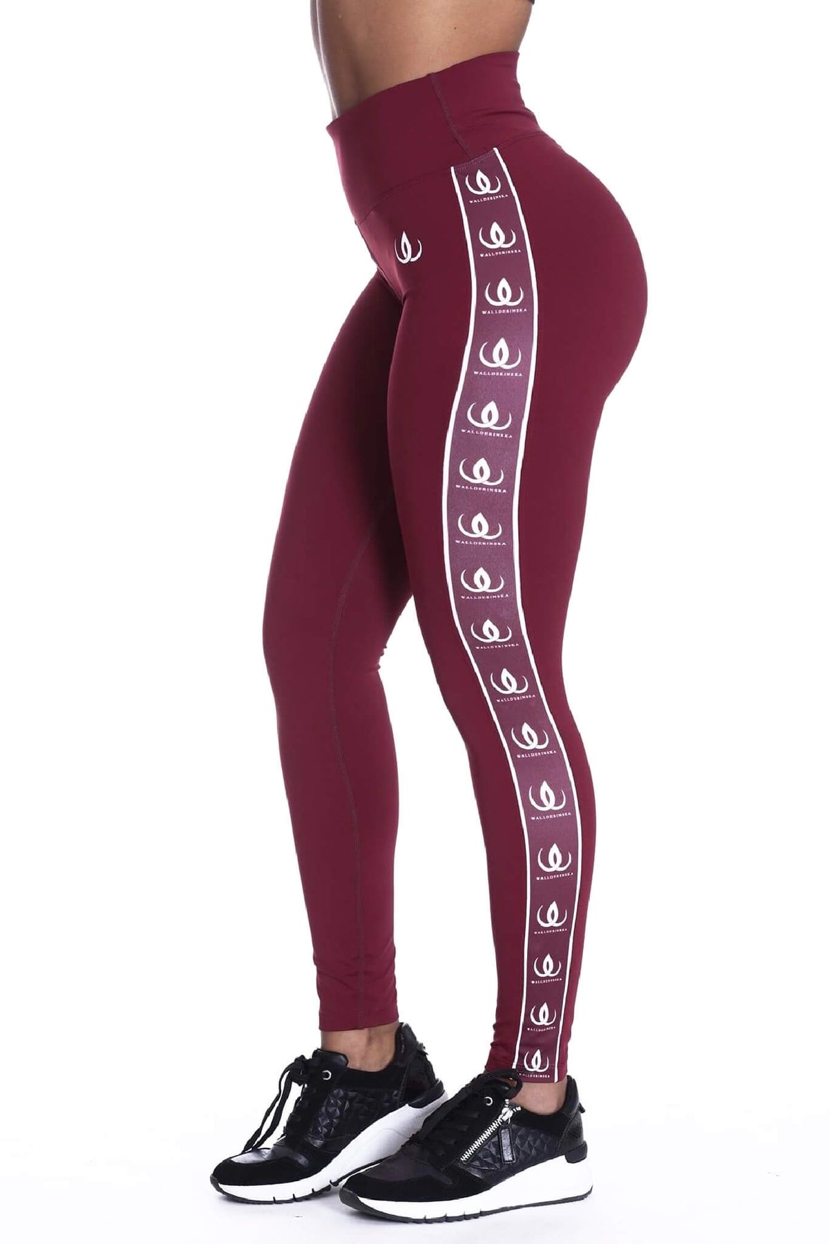 La taille haute du legging bordeaux, avec une bande logo blanche sur le côté et des chaussures noires en bas.