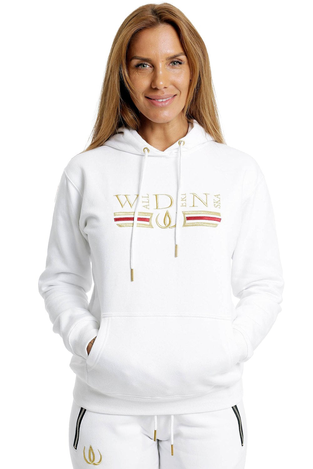 Deluxe Hoodie blanc à broderie dorée et rayure rouge sur la poitrine, porté avec un jogging blanc.