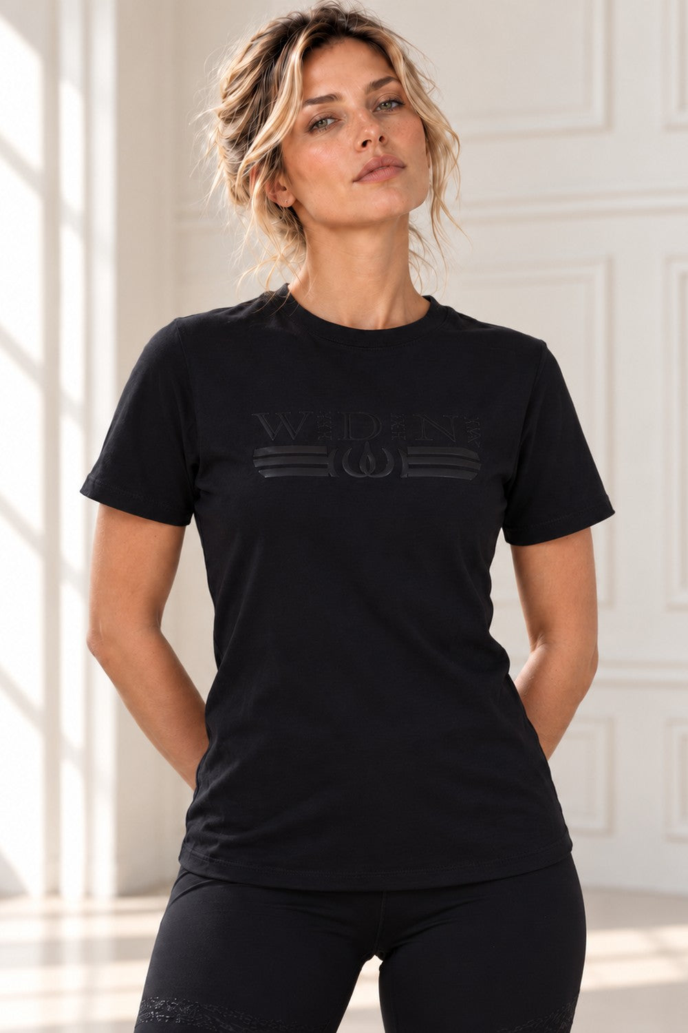 Haut Deluxe noir avec logo dans le même noir, porté avec un legging noir.
