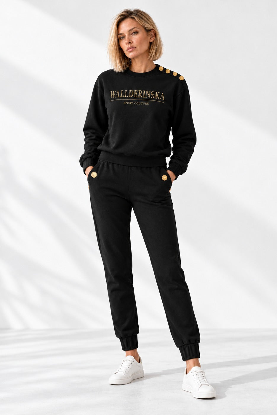 Pull Edge Gold Button et Pantalon Edge Gold Button en noir, en pied en studio avec des sneakers blanches.