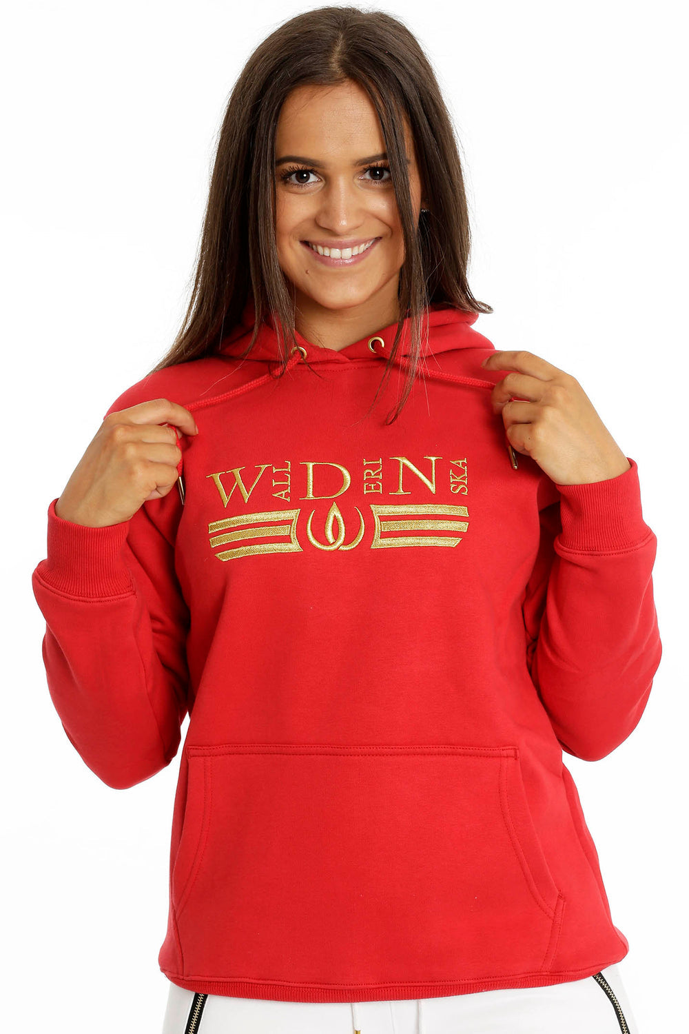 Les cordons de la capuche sont tenus dans la main. La broderie dorée court sur la poitrine du hoodie rouge.