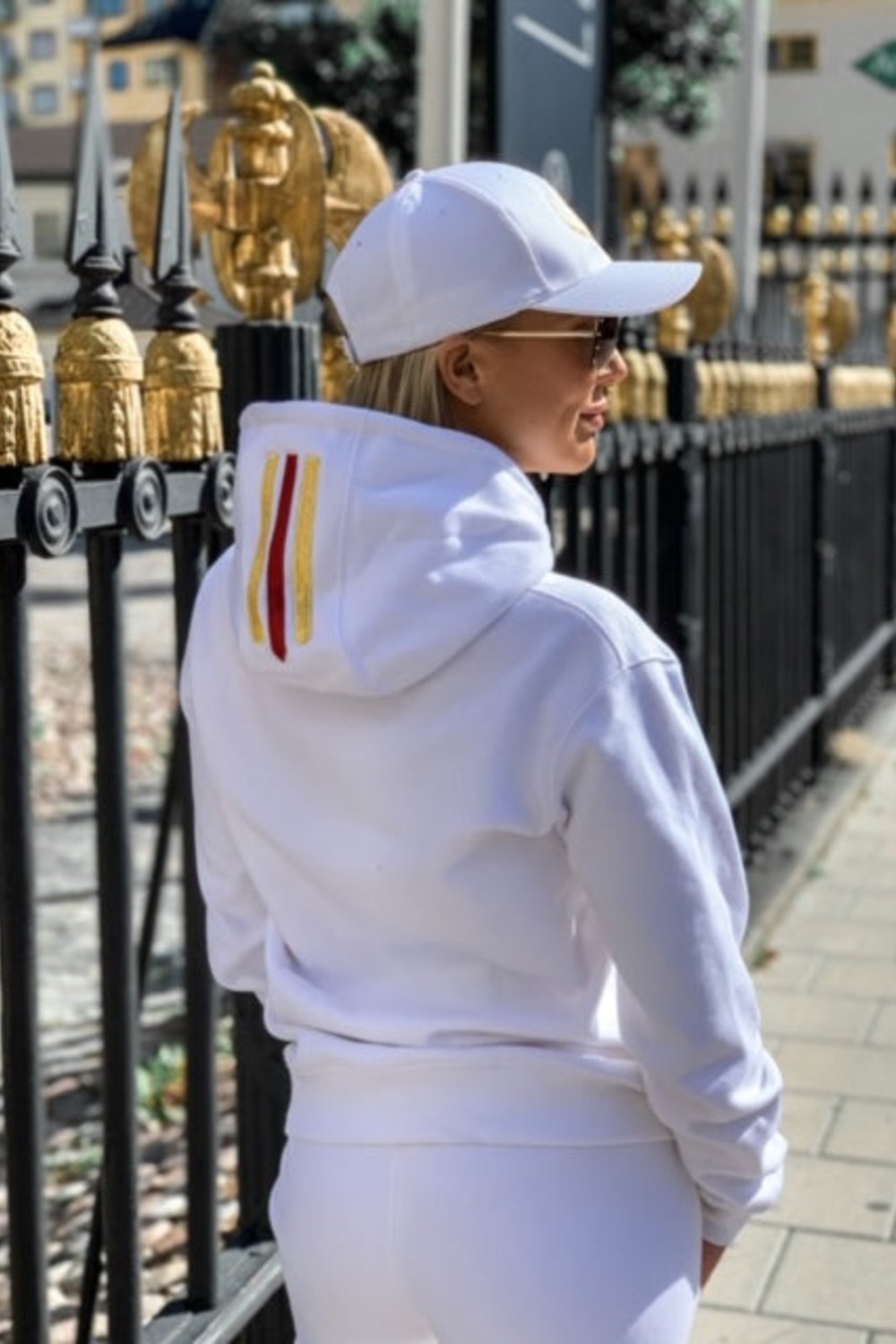 L'or et une rayure rouge sur la capuche apparaissent quand le mannequin se tient face à une clôture noire.