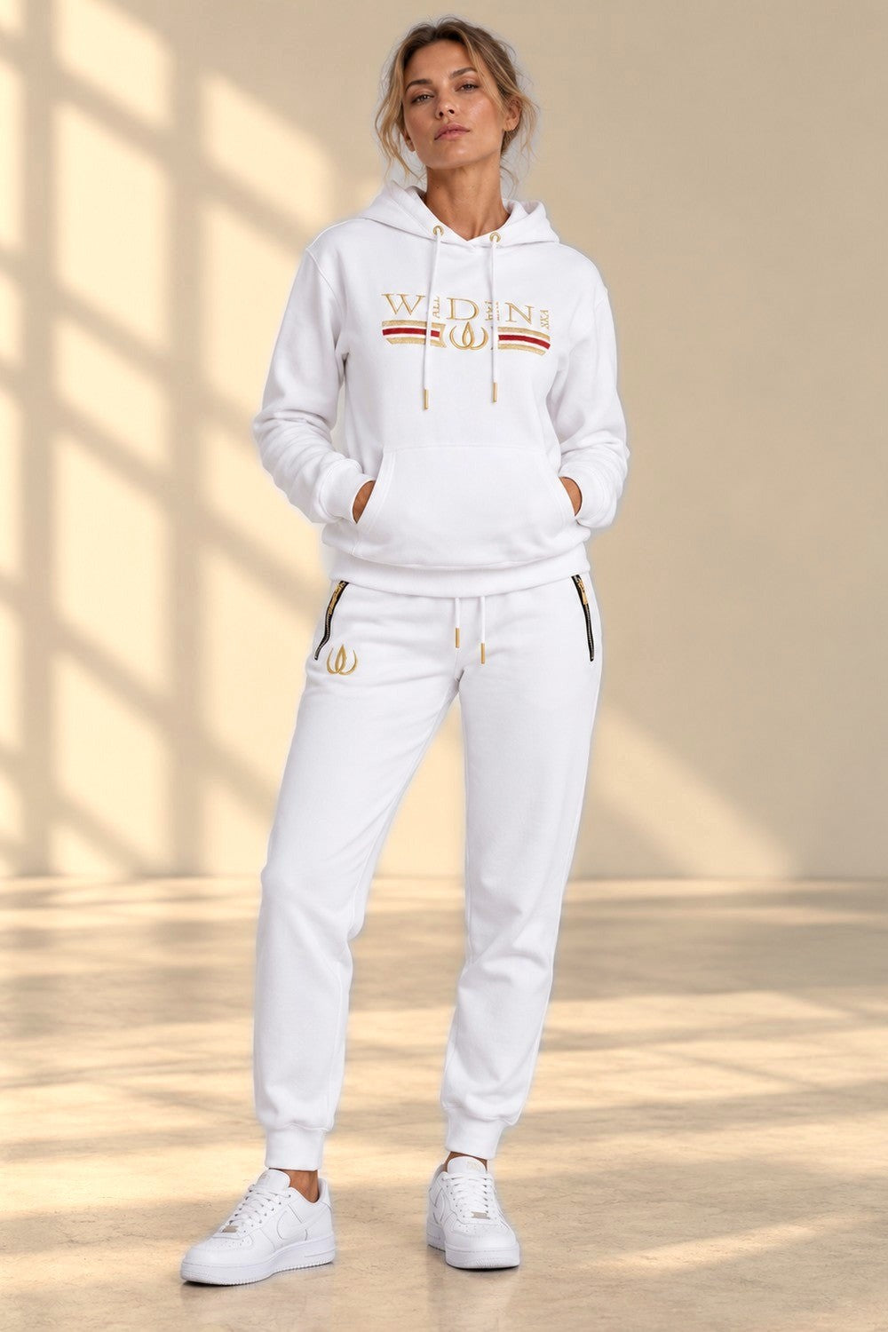 Ensemble sweat blanc de Deluxe avec broderie dorée sur la poitrine et bords côtelés aux chevilles.