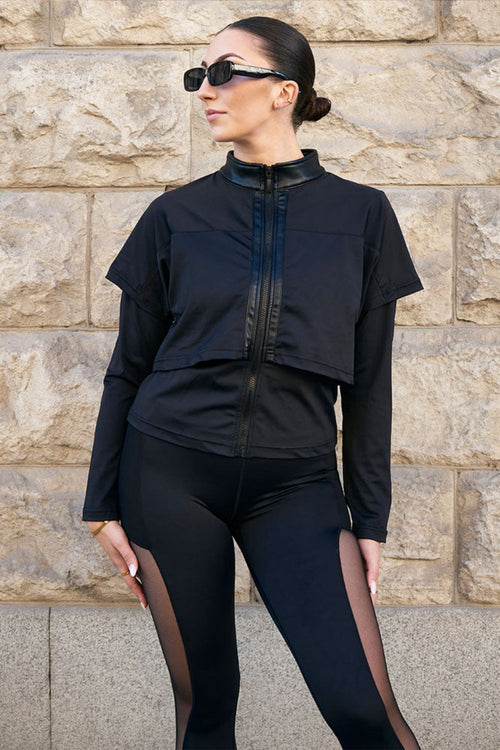Veste d'entraînement noire Edge avec col brillant et épaisseurs sur les épaules, portée avec un legging noir avec mesh.