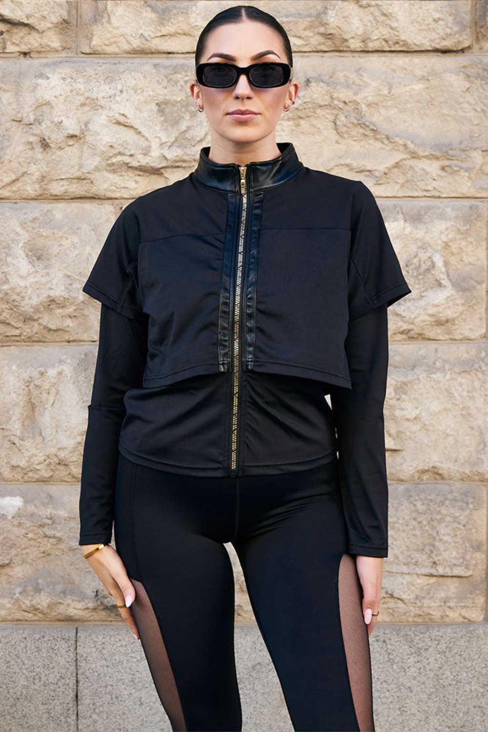 Veste d'entraînement Edge Gold Zip avec zip doré sur le devant, portée avec un legging noir avec mesh.